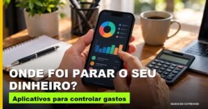 Mãos segurando um celular com aplicativo de controle de gastos sobre a mesa de trabalho